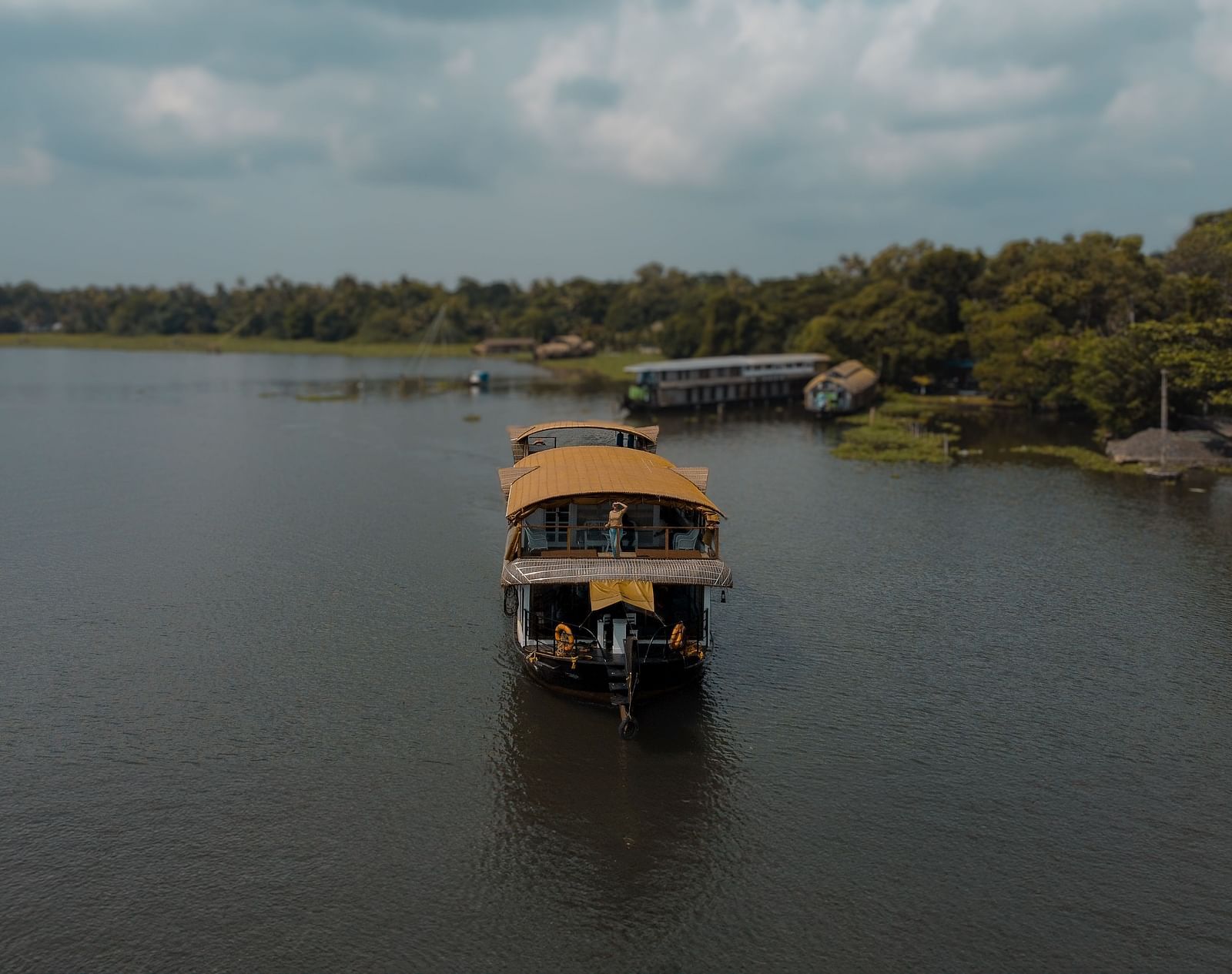 A cruise sailing across the Vembanad Lake with lush greenery in the background - BluSalzz Villas - Muhamma Resort, Alleppey