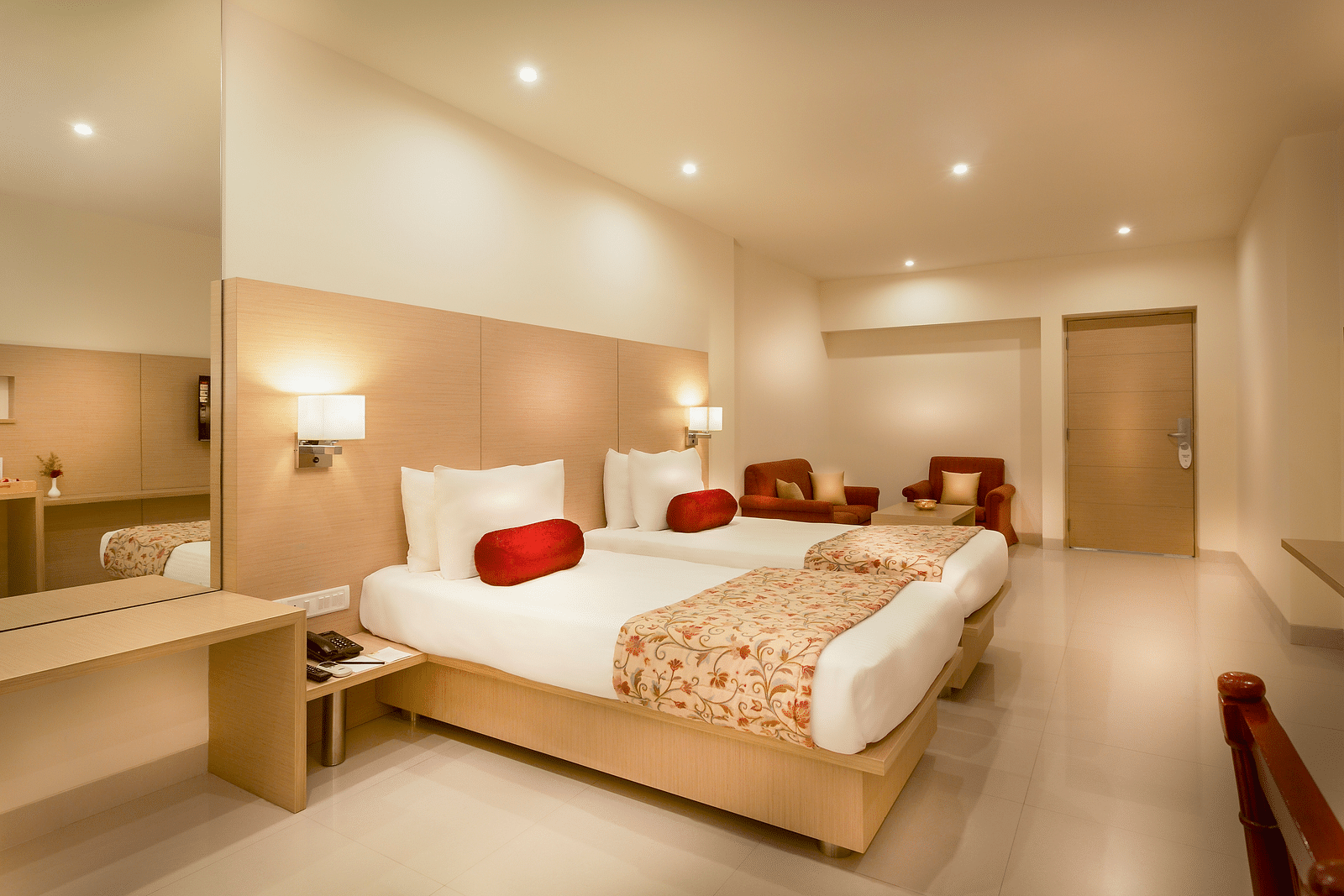 An image of a king size bed with a work desk and TV of a Suite at Regency Tiruttani by GRT Hotels.