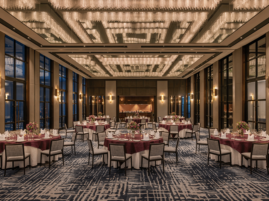 Gallery function room set up for a gala dinner with round tables at twilight at The Residency Signature Madurai.