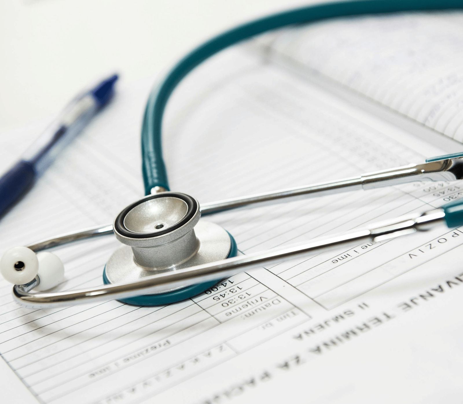 A stethoscope placed on medical documents with a pen beside it on a desk.
