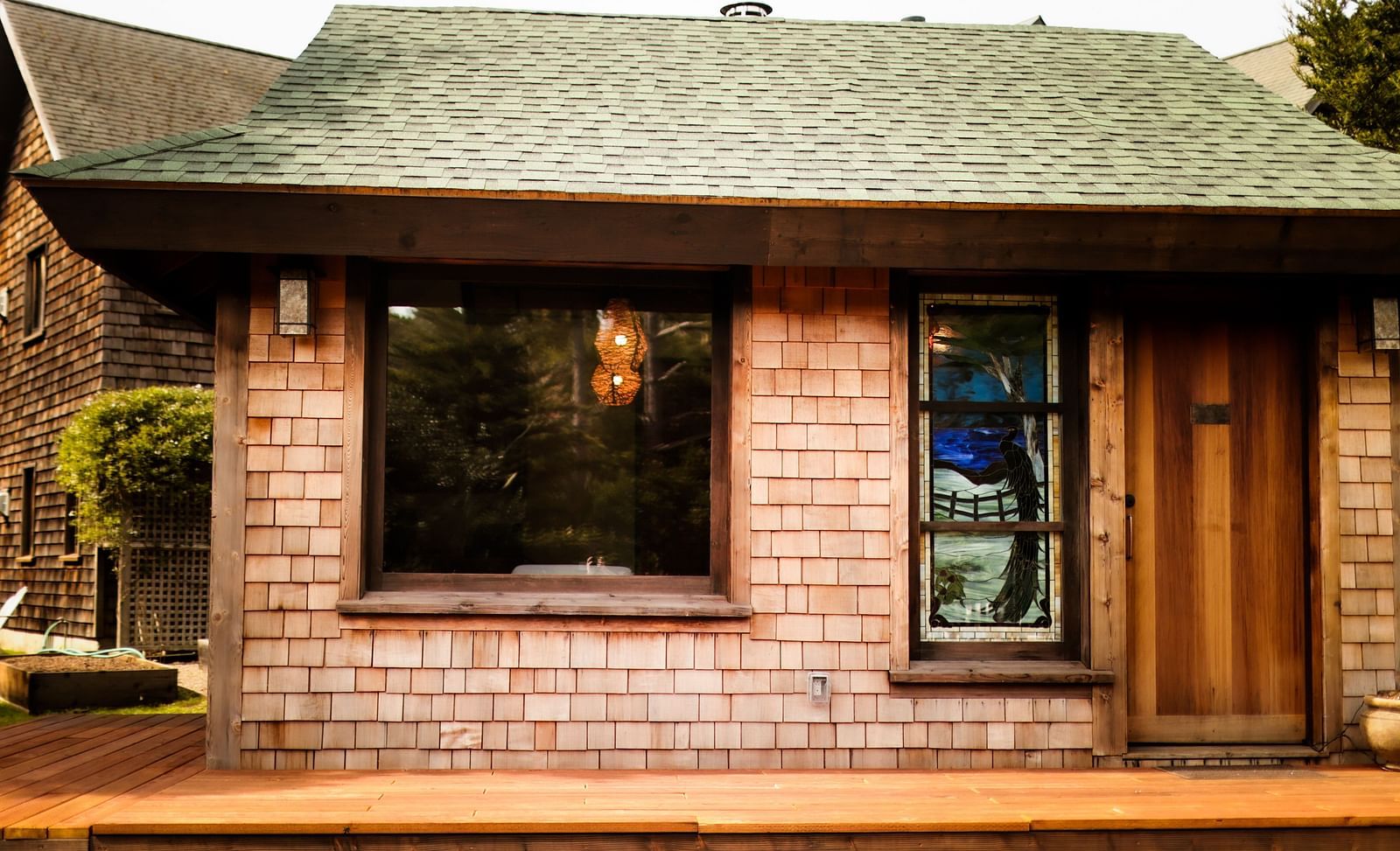 Exterior view of a rustic cabin with wooden siding, green roof, and large windows - Brewery Gulch Inn & Spa