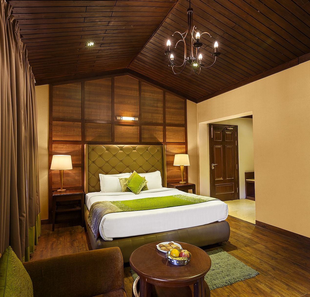 a bedroom with a large bed and side lamps, a table and a sofa - The Earl's Court, Nainital