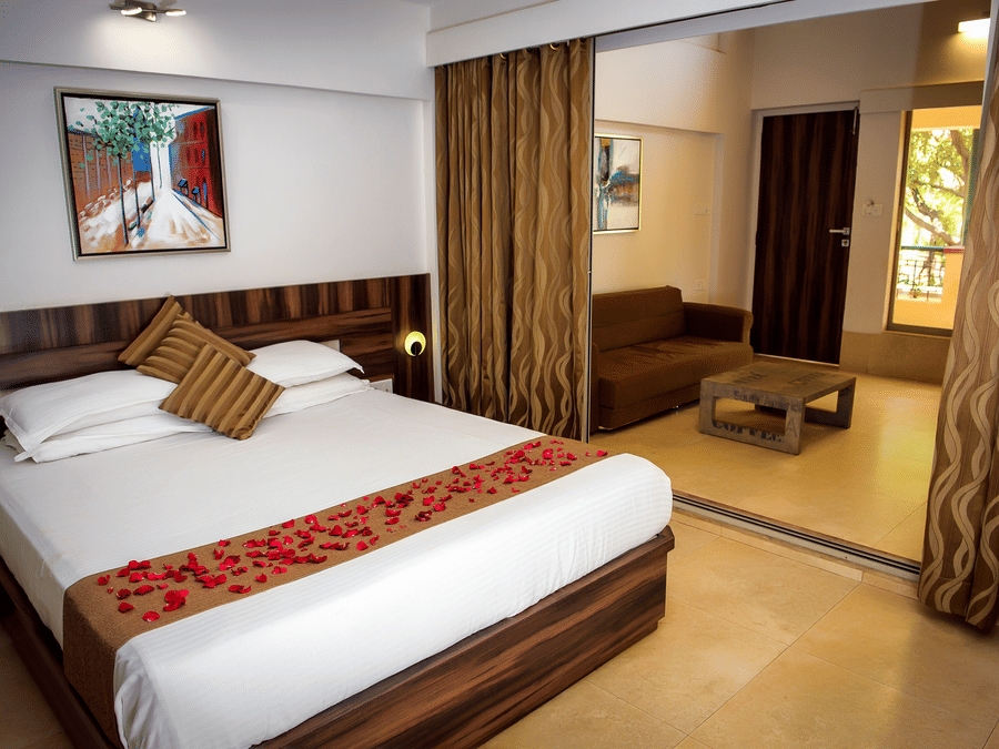 Deluxe villa bedroom interior featuring a bed, sofa and coffee table - Adamo Resort Matheran.