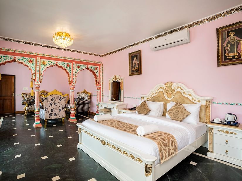 The pink walls and white bedding at the Maharaja Suite Bedroom - Stone Wood Riverfront Resort, Siolim