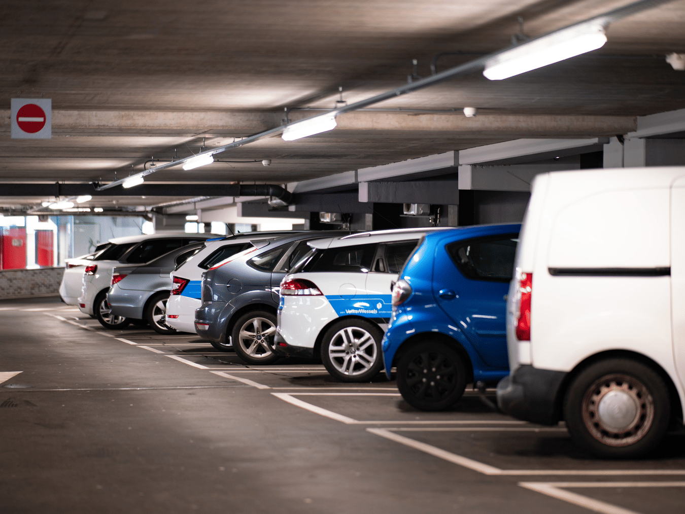 many vehicles parked in a parking lot inside a building
