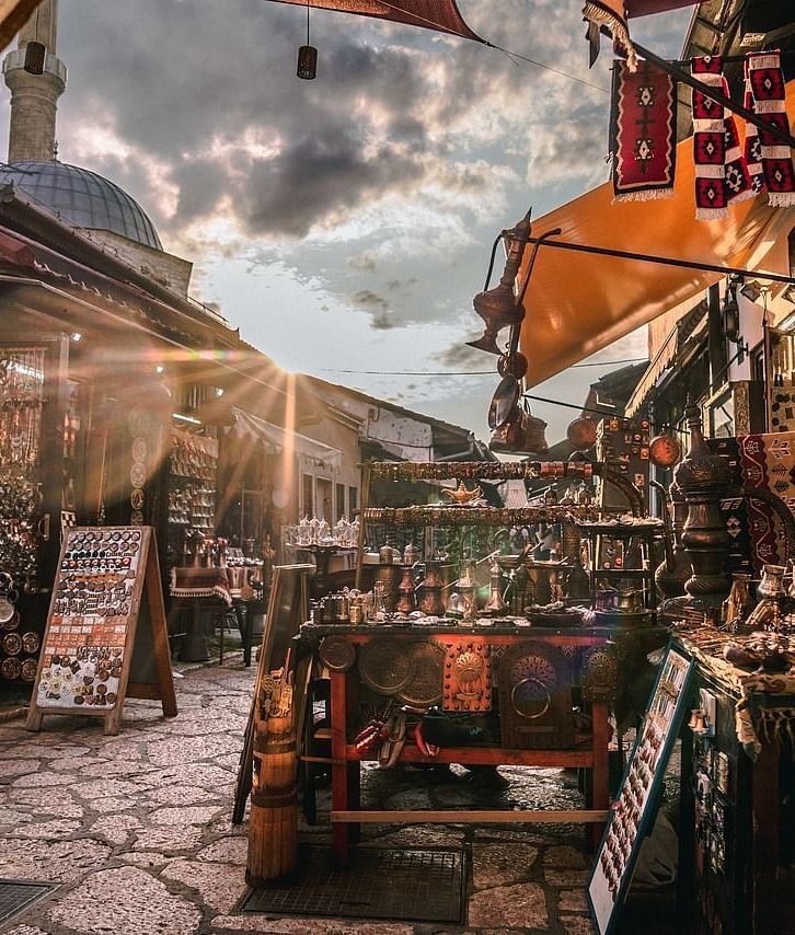 A bustling street lined with shops and vendors, bathed in the warm light from the sun, showcasing a lively atmosphere