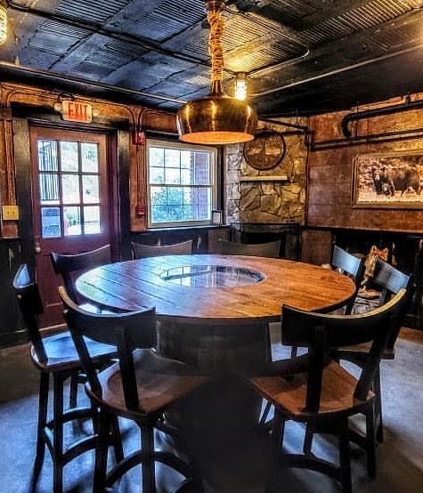 a circle shaped table surrounded by wooden chairs in a dimly lit room - Historic Tapoco Lodge