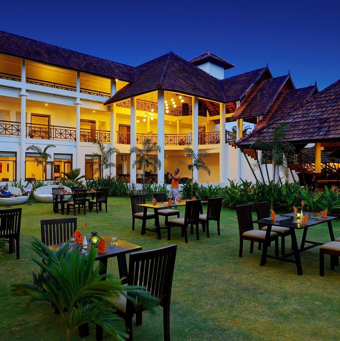 Dining chairs arranged on a green lawn - Rhythm Kumarakom