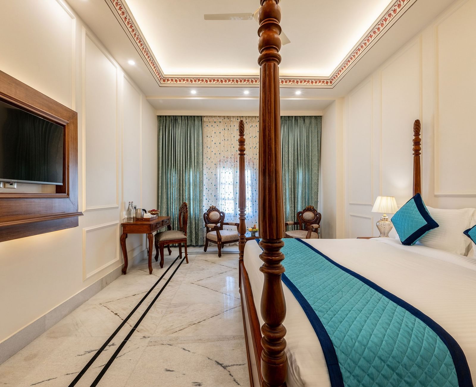 a luxurious and well ventilated bedroom featuring a double bed along with a common seating area at the far end of the room - Brij Castle, Jaipur