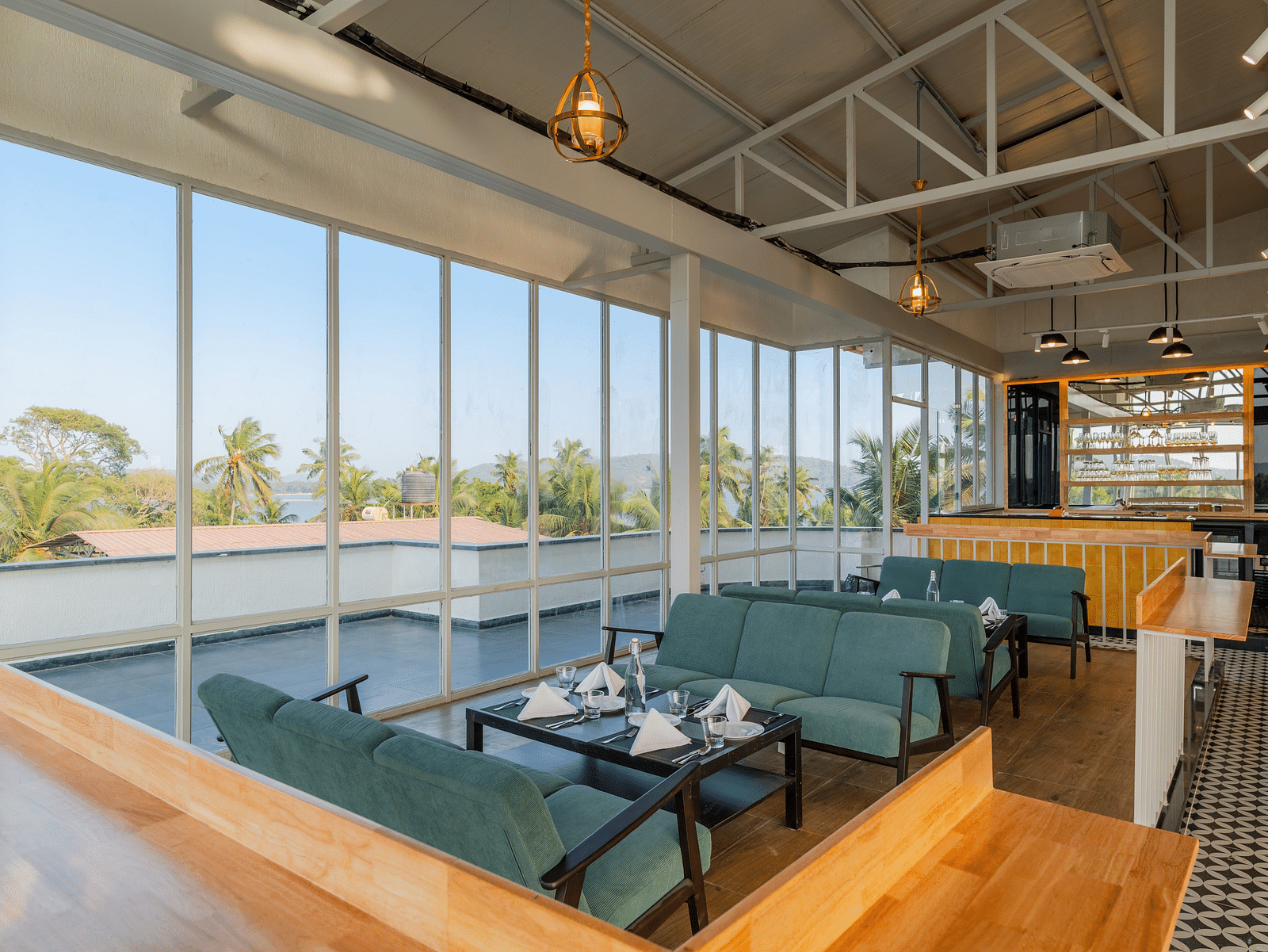 Spacious cafe interior with large windows and comfortable seating at Bedzzz Xclusiv Morjim, Goa