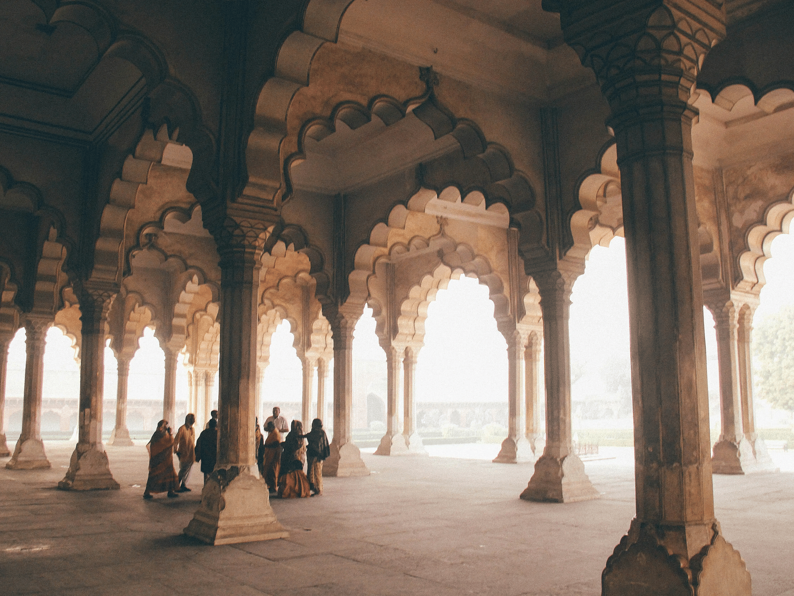 A group of people standing near pillars of a building twmwlx