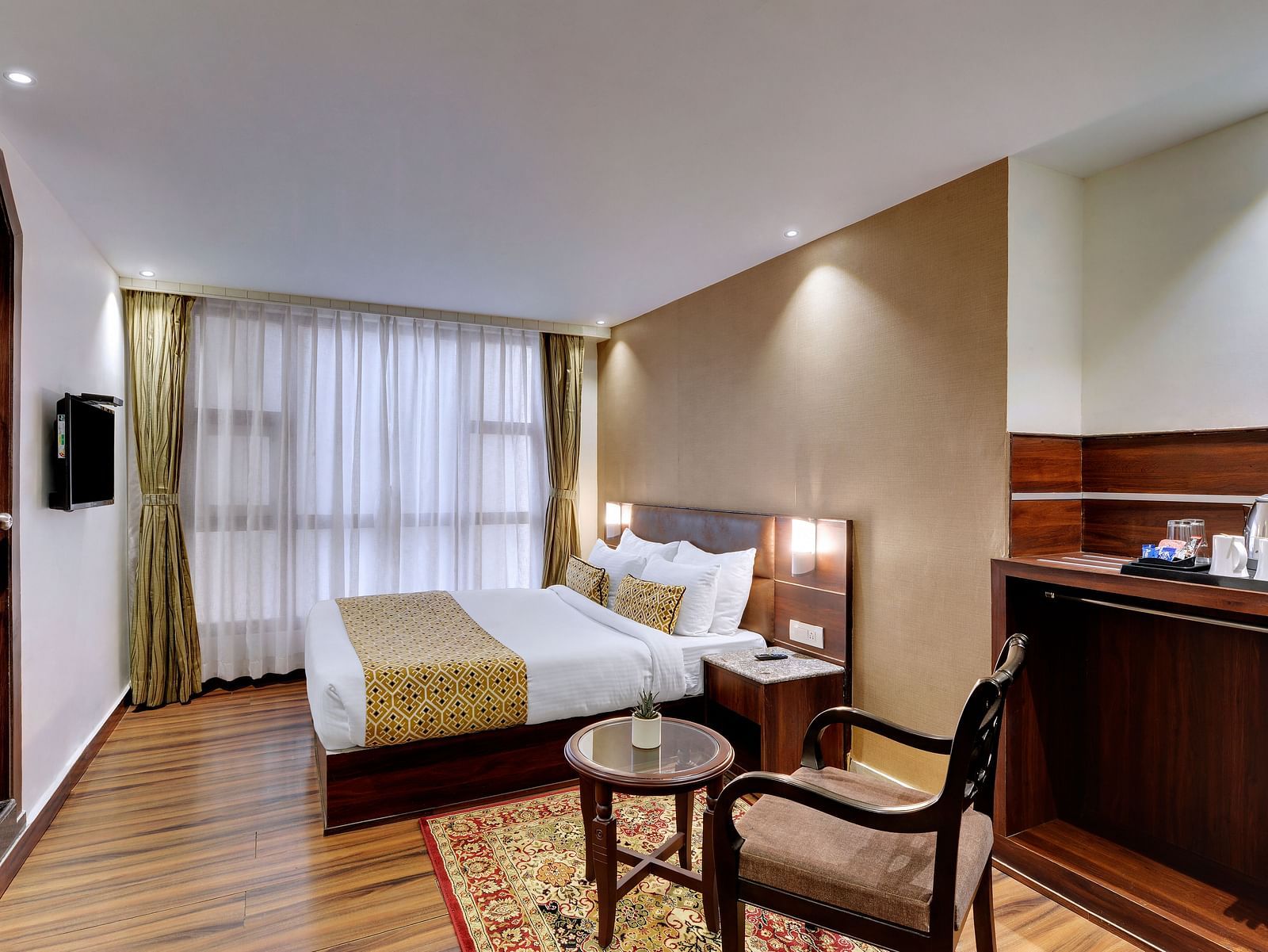 An image of a room with a queen size bed, TV, chair and a table, and room amenities like tea coffee maker - Sumitel Vista TV Tower