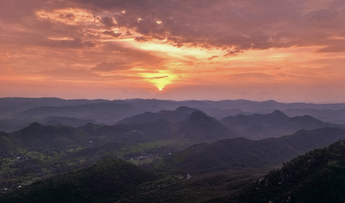 Sunset over layered hills with a landscape view.