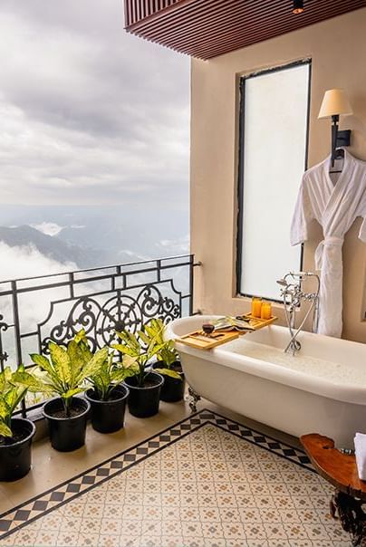 Balcony with bathtub, railing, potted plants, and valley view at Polo Resort Cherrapunjee.