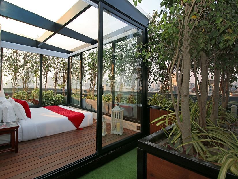 An image of a bedroom with glass windows next to potted plants in the terrace - Theory9 - Premium service apartments, bandra