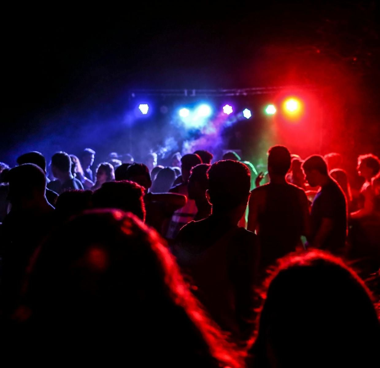 A group of people in a dark room partially lit up with red and blue stage lights.