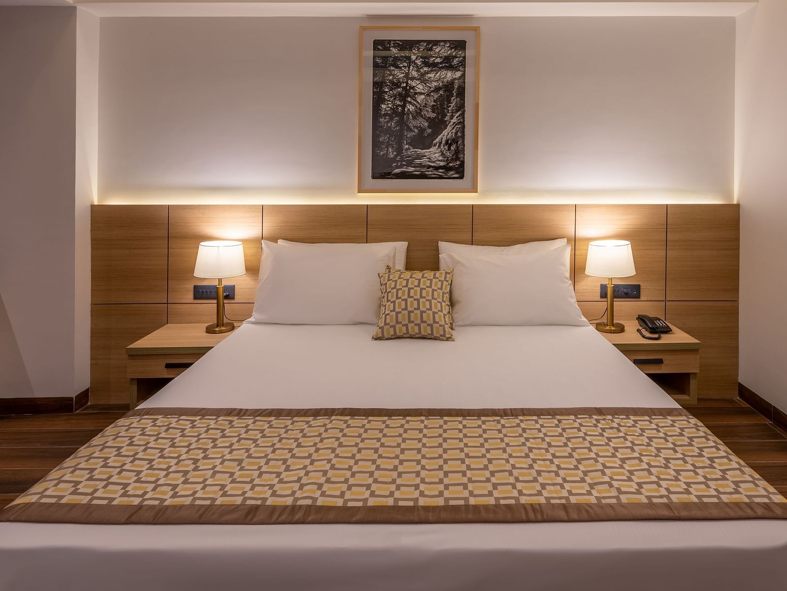 Close up of Premium Room at Vishranti Hotel, Dehradun featuring a king bed with side tables and bed lamps. 
