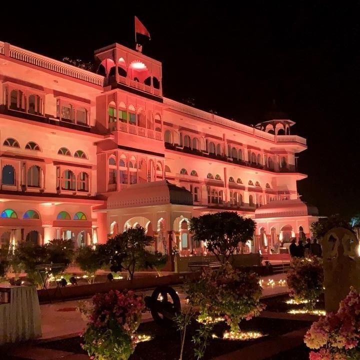 Front Facade of  Umaid Palace Dausa featuring a stretched and multi storey building lit with red light at night for an event.