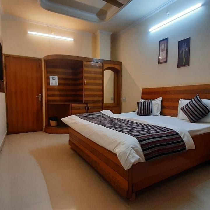 An image of our Semi Deluxe Room equipped with a queen size bed, a cupboard, and a wall-mounted television - Motel Divine International, Roorkee