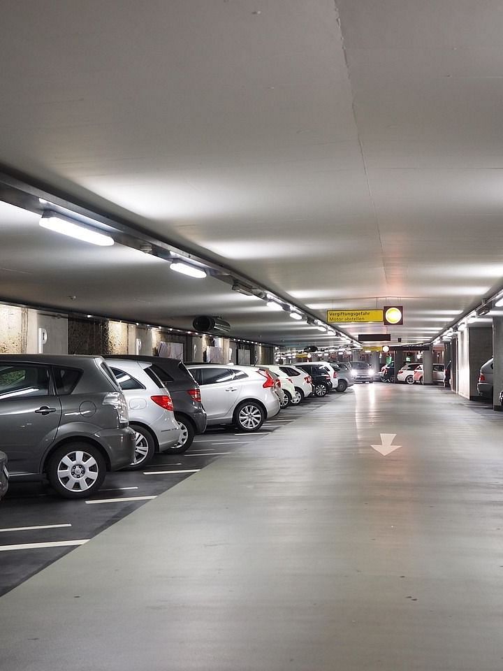 An underground car park with rows of parked cars extending into the distance under artificial lighting.