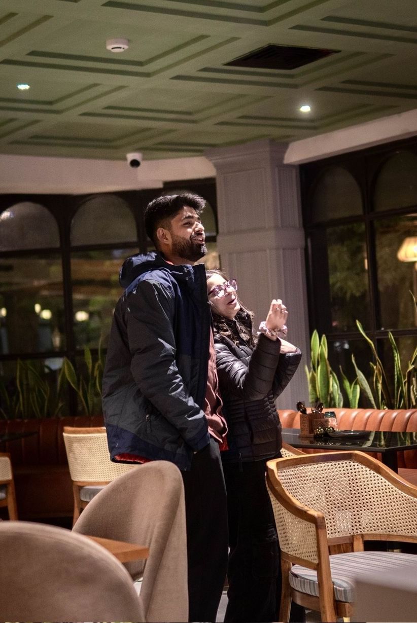 A couple enjoying themselves in a lounge at the Polo Hotel Shillong, with a person in the foreground.