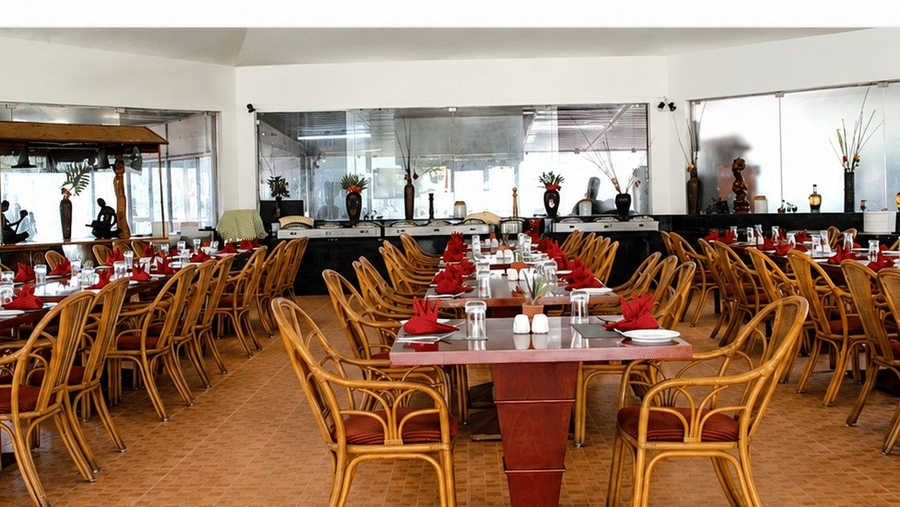 Kapi Restaurant dining area with wicker chairs and red table accents at Chariot Beach Resorts, offering a warm and inviting atmosphere