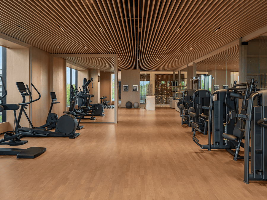 Gym with rows of cardio and strength training equipment on wooden flooring at The Residency Signature Madurai.