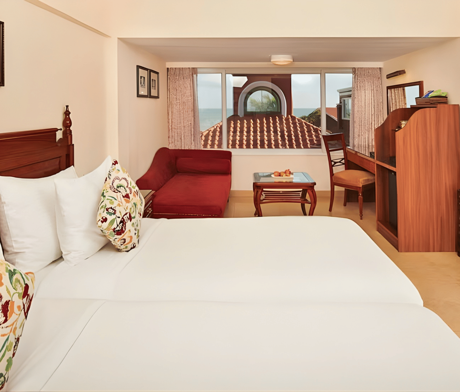 Bright and airy twin bed room at MAYFAIR Heritage Puri, featuring crisp white linen, colorful floral cushions, and a cozy seating area near the window.