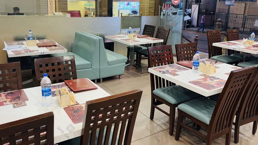 Casual dining area with neatly set water bottles, menu card, spoon stand on the table and modern decor at Hotel Dr Rajkumar International restaurant.