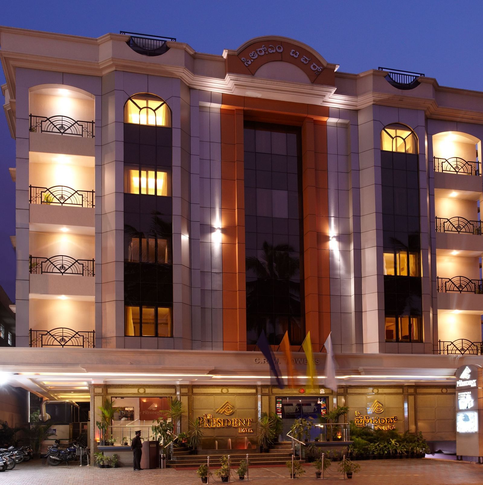 A facade image of a multi storey building with a parking area atThe President Hotel Jayanagar Bangalore 