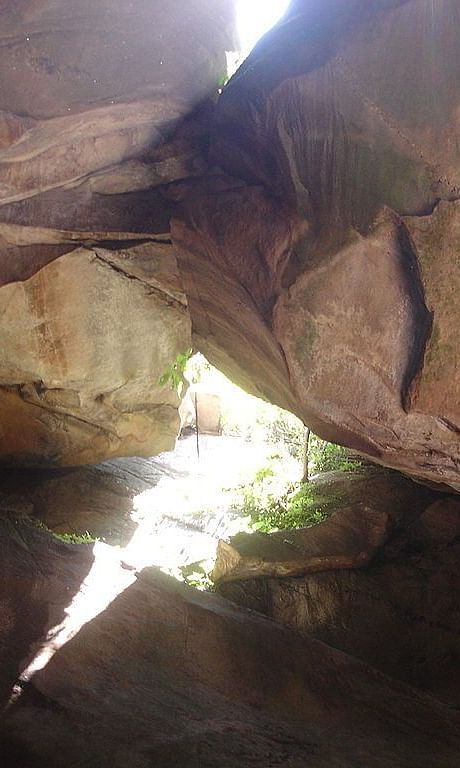 Inside view of an old cave, showing rough stone walls lit by sunlight coming through an opening
