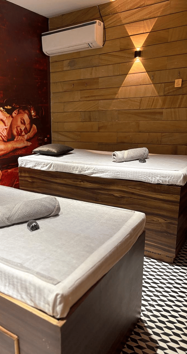 Two SKYN Spa treatment beds with rolled towels against a wood-panelled wall with a warm wall light