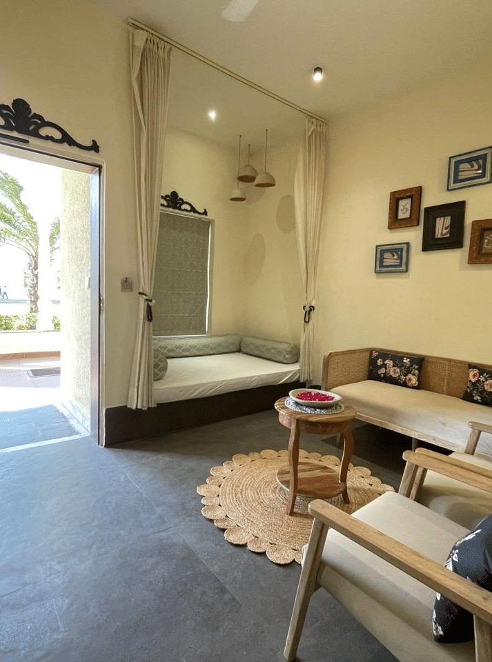 Indoor seating area with sofa, table, open doorway and wall art at Beelwa Palace, Jaipur