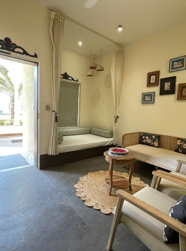 Indoor seating area with sofa, table, open doorway and wall art at Beelwa Palace, Jaipur