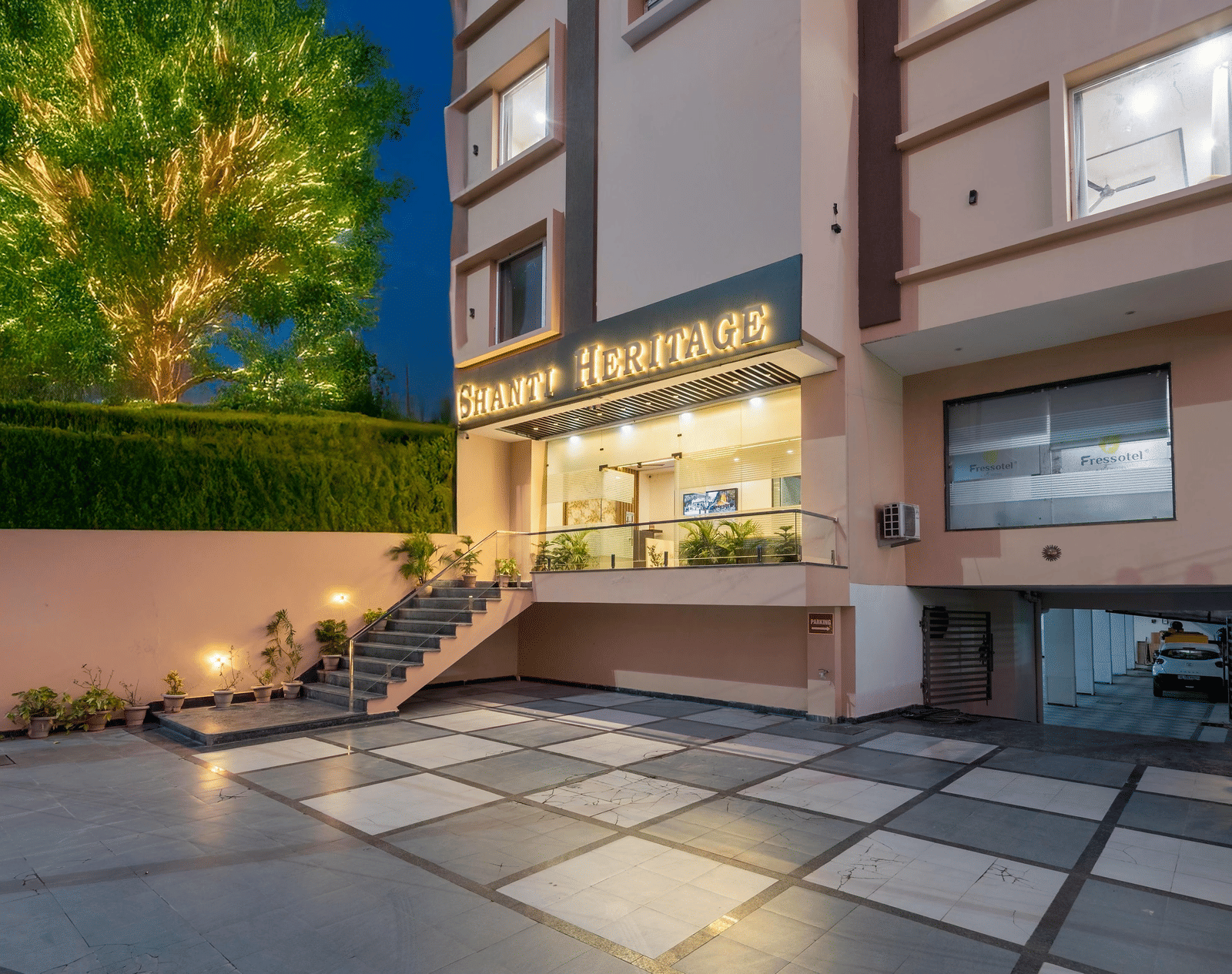 The hotel building entrance and paved driveway at late evening showing trees at Perfectstayz Premium Shanti Heritage, Haridwar