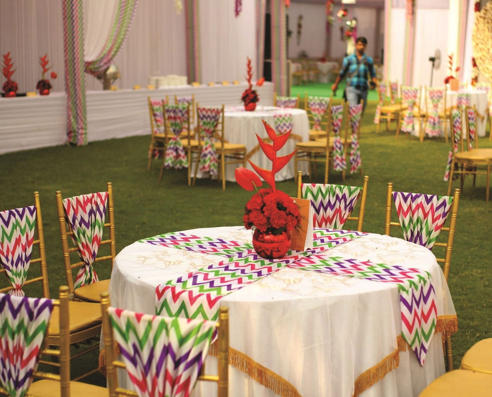 Chairs around a table with colourful printed covers and floral centrepieces | Gemini Continental