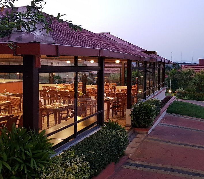View from outdoor area of a restaurant in a wooden structure and lush greenery | Sheesham Restaurant | Woodstock Resorts, Coorg