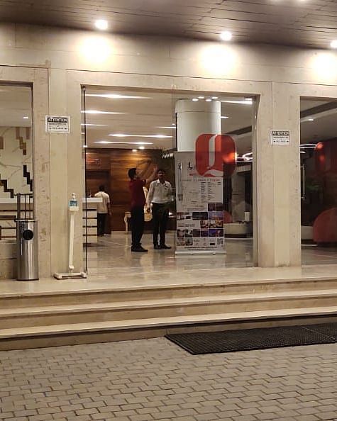 The entrance to a building with glass doors, potted plants, and people entering or leaving.