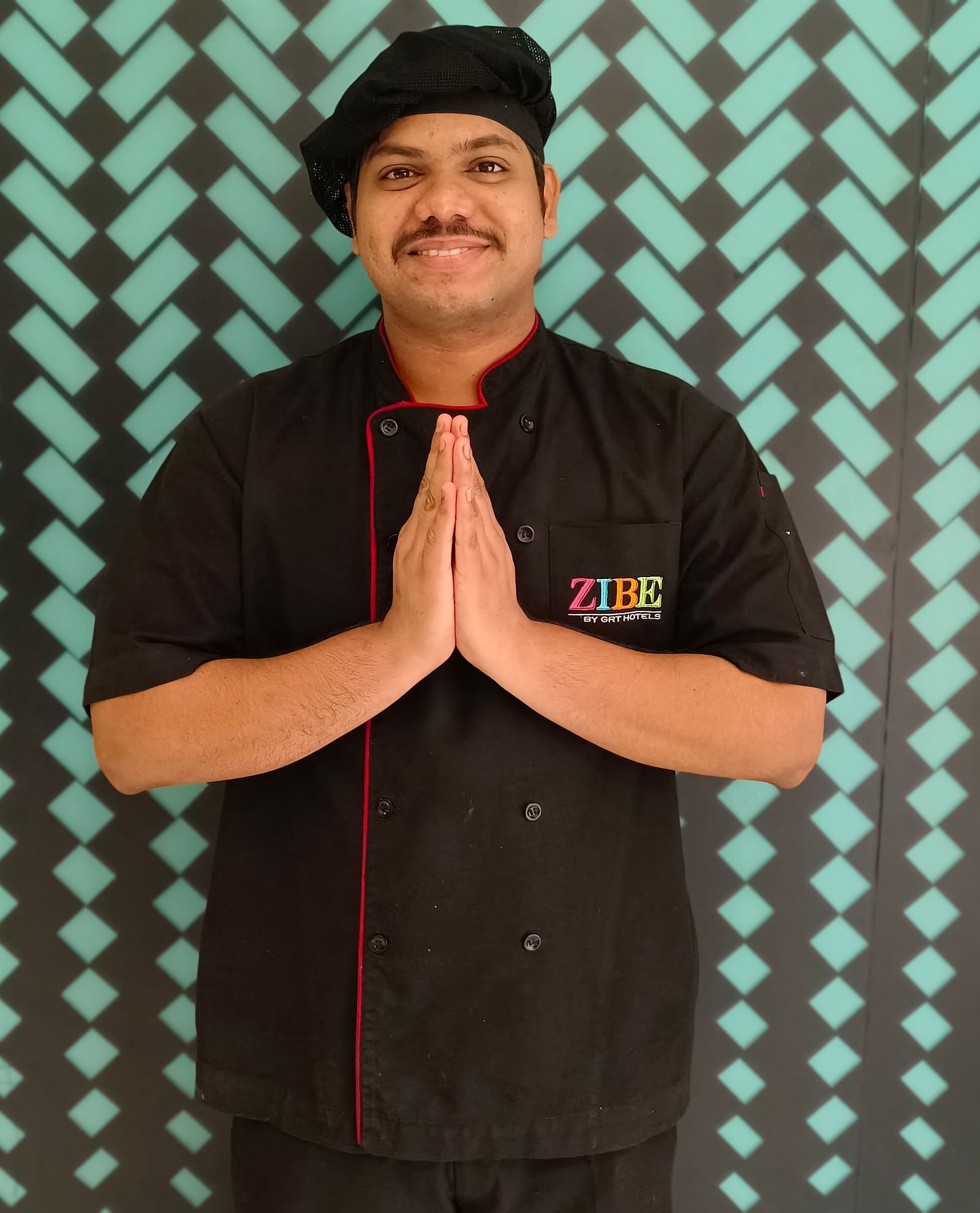 MR. Sai Durga stands with poise against a backdrop featuring a repeating pattern.