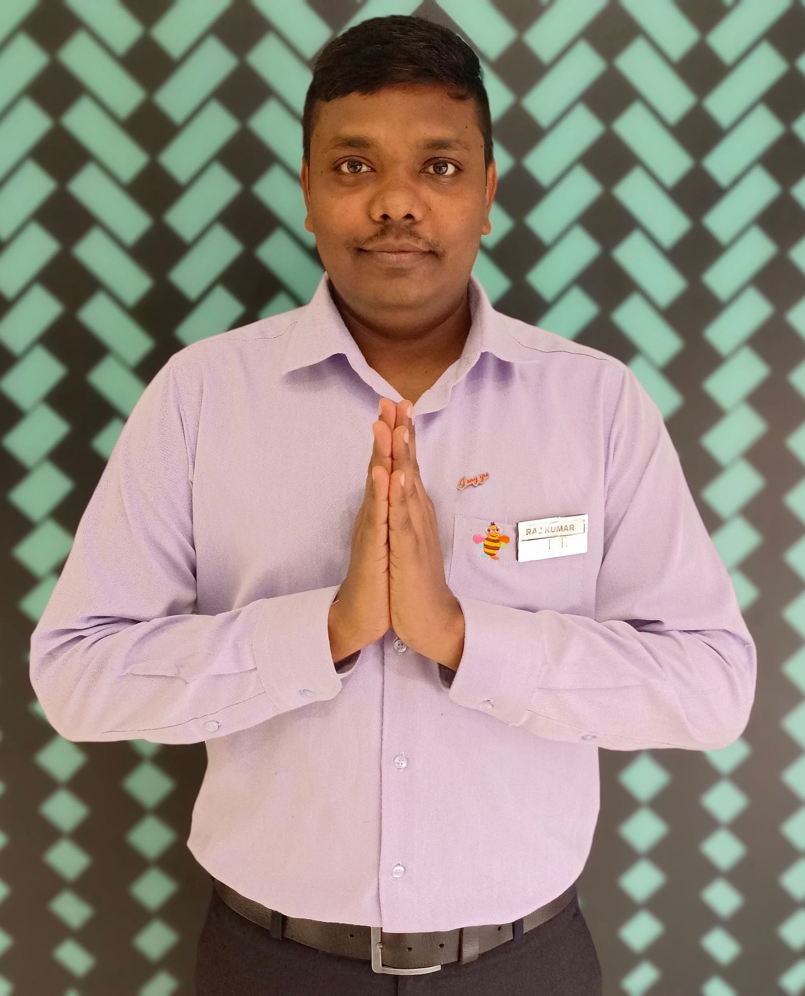 Mr. Rajkumar stands with poise against a backdrop featuring a repeating pattern.