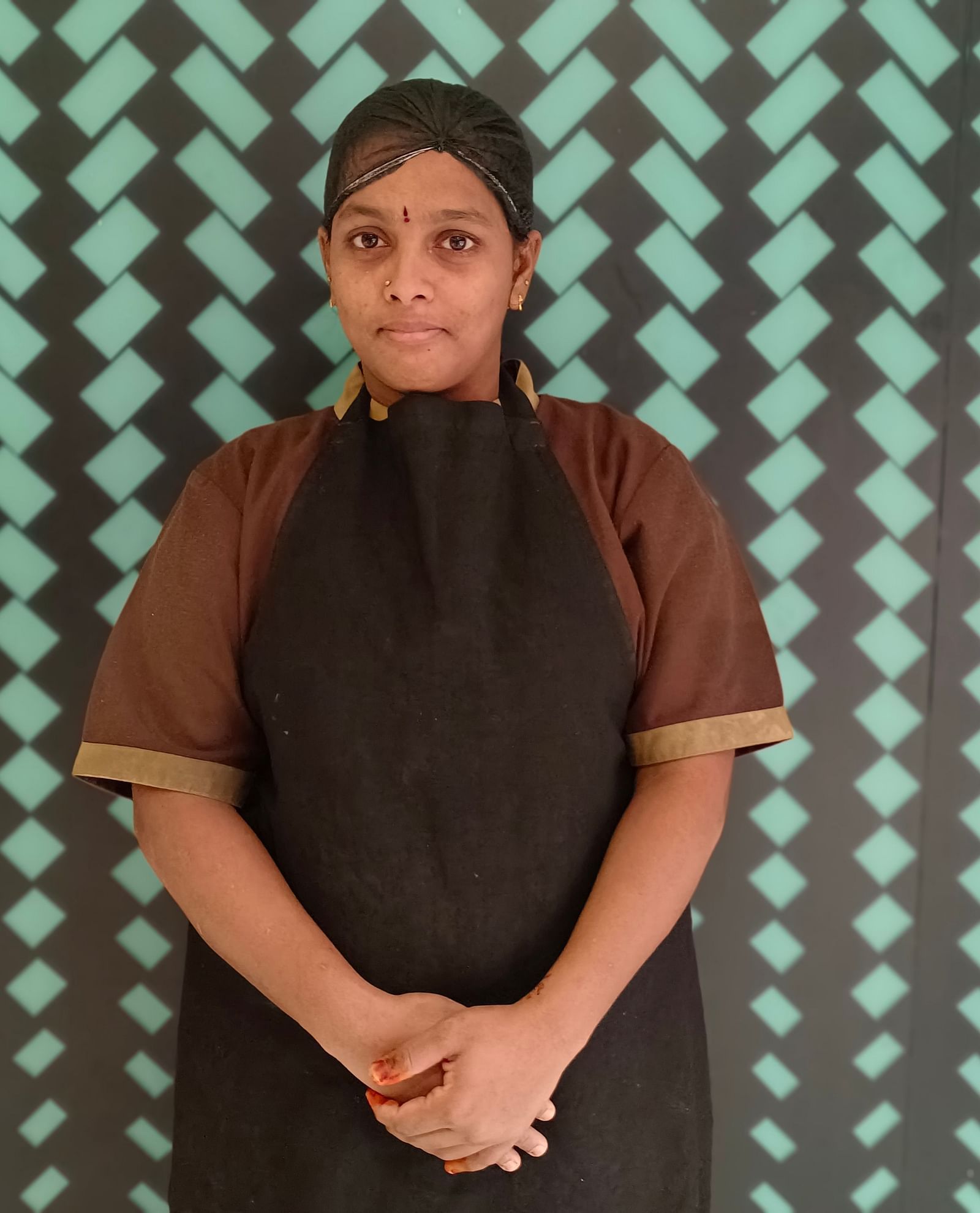  Mrs Naghavi stands elegantly against a background with a repeating pattern
