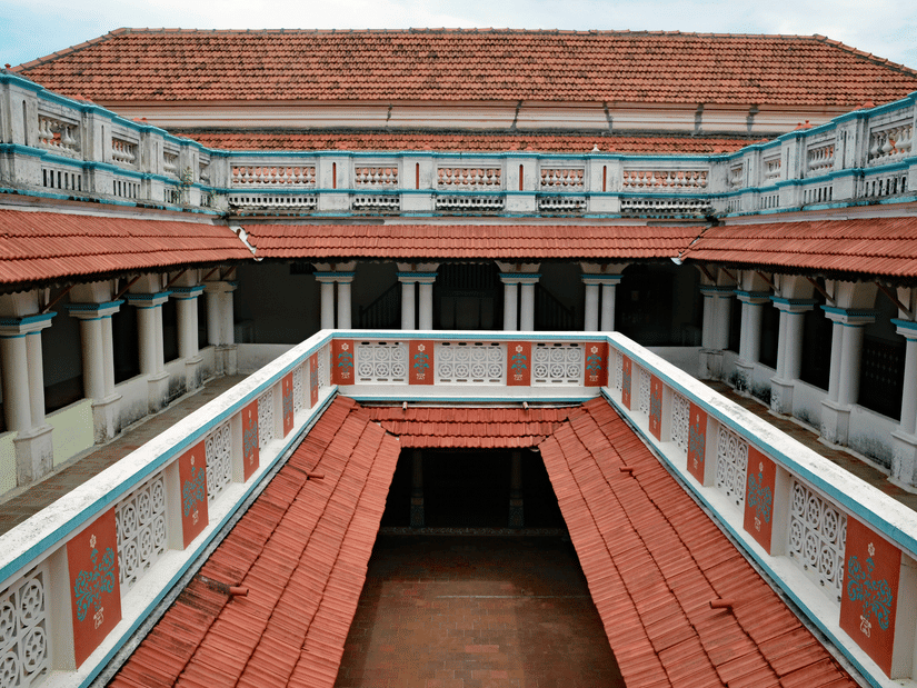 A view from the top floor of a courtyard inside a Chettinad Palace with numerous pillars and tiles also in view.