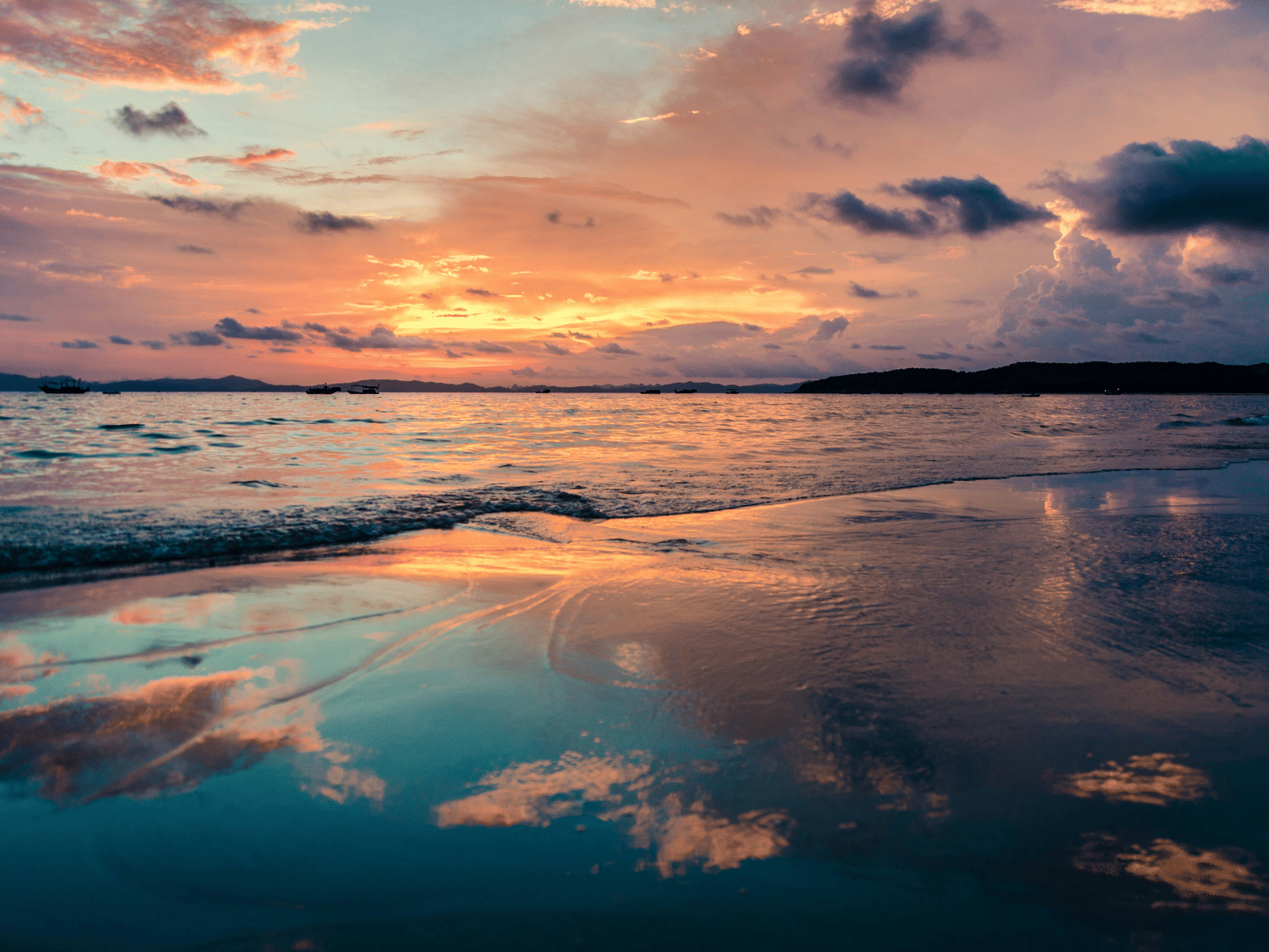 A stunning sunset reflecting across still waters, with golden light, soft clouds and vibrant hues creating a peaceful and immersive evening seascape.