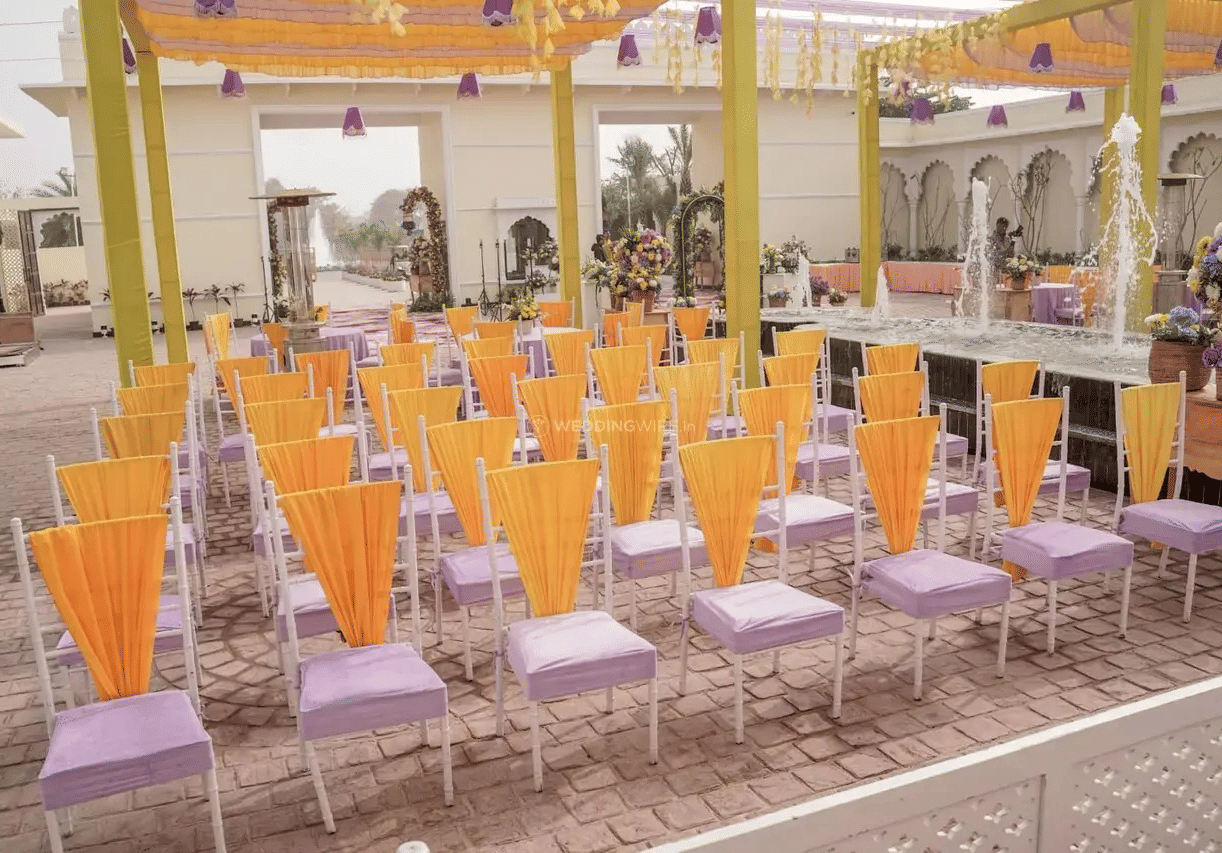 Outdoor seating area arranged with rows of yellow and purple chairs for event at Beelwa Palace, Jaipur