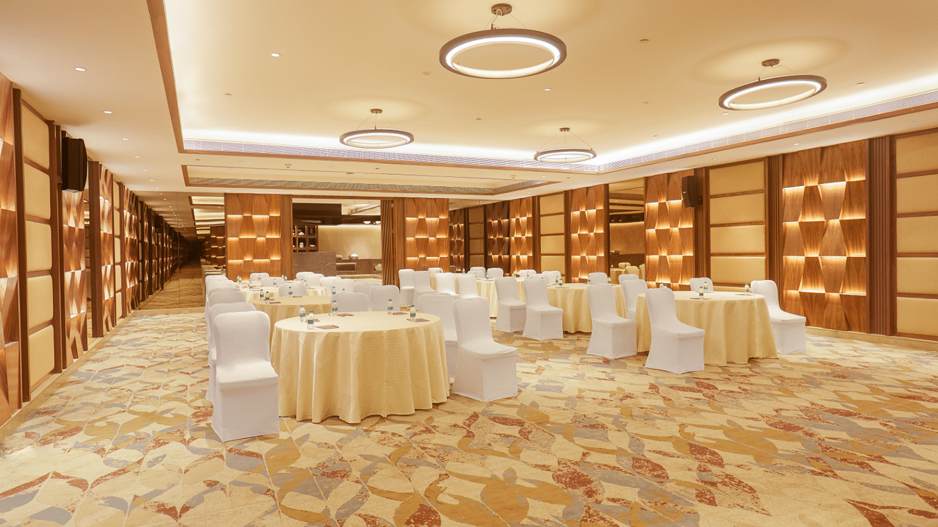 A front corner view of the banquet hall at The Residency Tower, Chennai, featuring round tables and elegant chair seating.