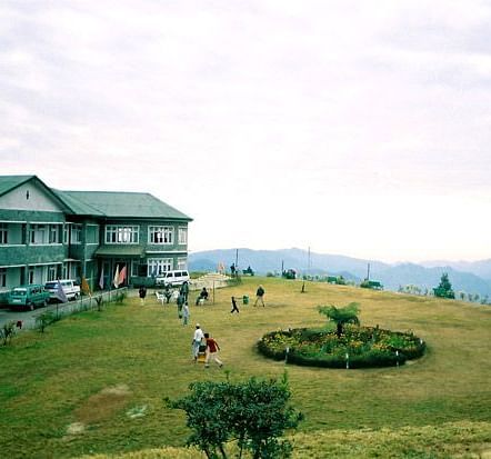 View of a lawn with a building with hills in the far background