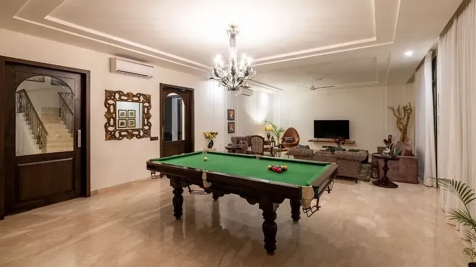 Room with a pool table, chandeliers, wall mirrors, and neutral-coloured decor at Karma Chalets.