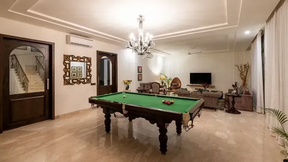 Room with a pool table, chandeliers, wall mirrors, and neutral-coloured decor at Karma Chalets.
