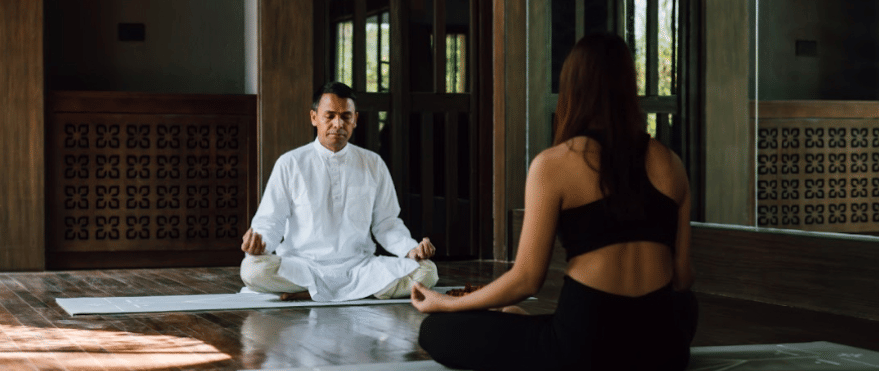 Two people practicing meditation in a room which has natural light at Kavya Resort and Spa, Nagark