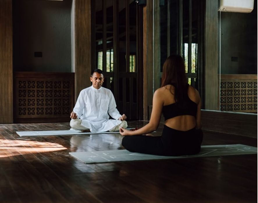 Two people practicing meditation in a room which has natural light | Kavya Resort and Spa, Nagark